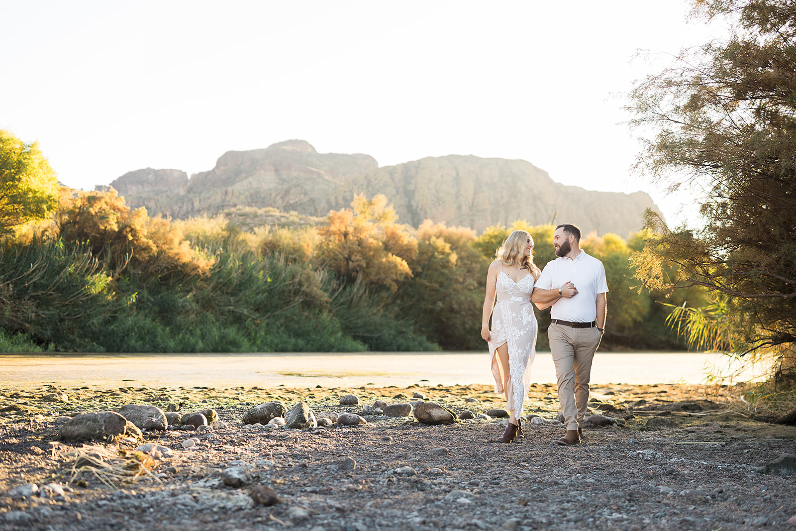 Couple walking and kissing along the Salt River during an engagement session