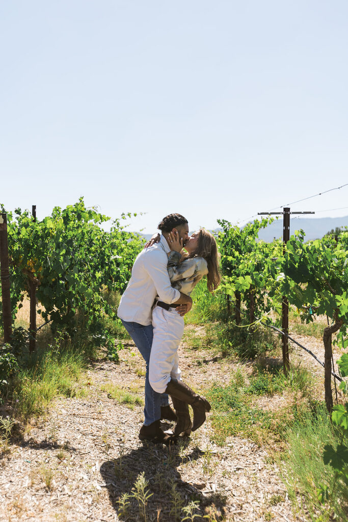 bride and groom kissing between grapevine rows