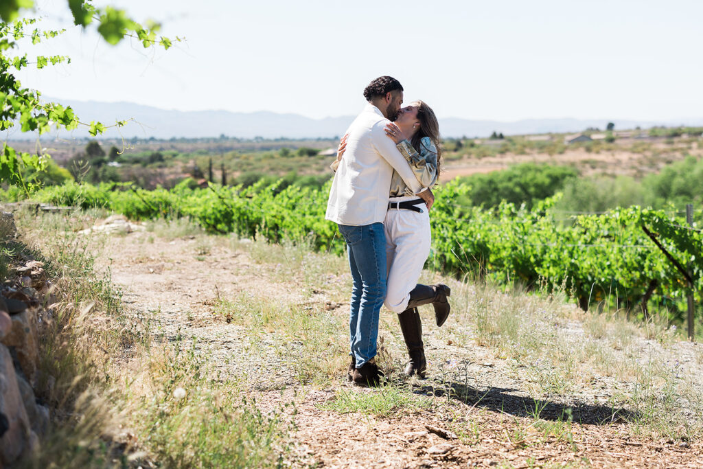 bride and groom embracing while spinning in vineyard