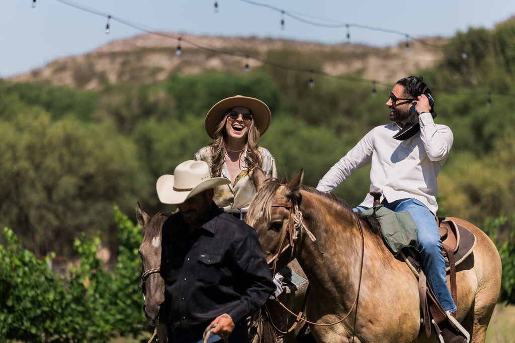 woman laughing on back of horse next to partner