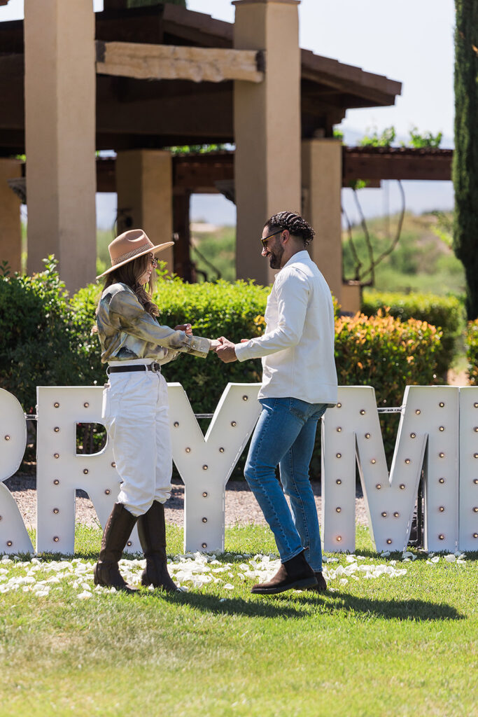 groom and bride in front of marry me sign