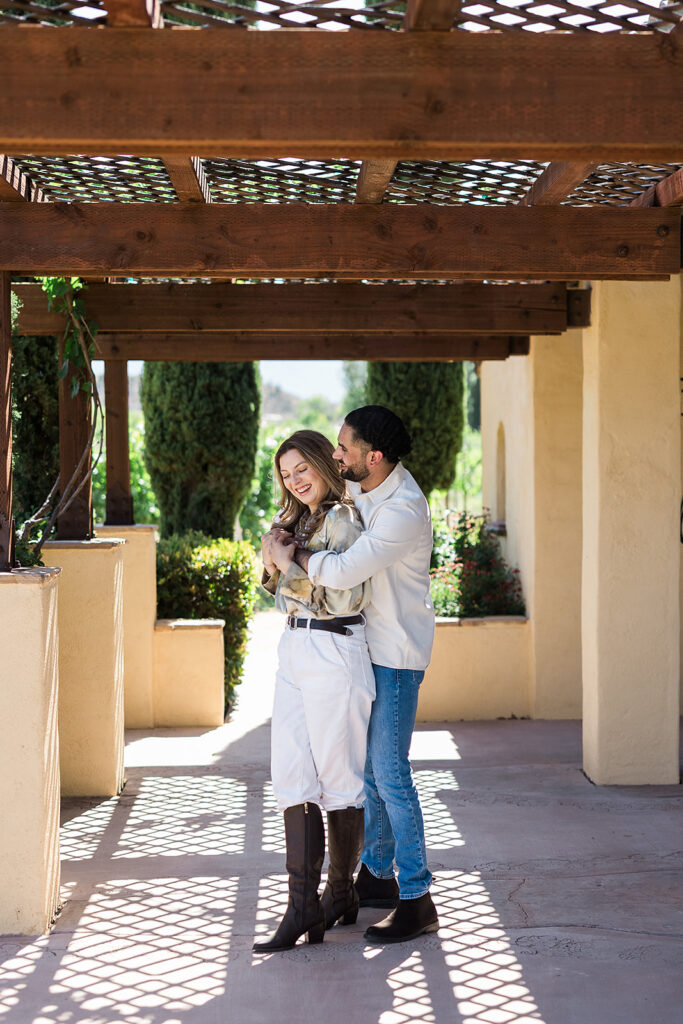 groom embracing bride under vineyard walkway