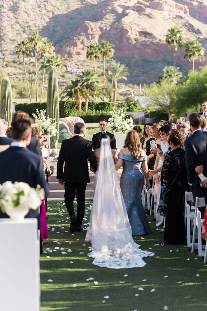 bride walks down the aisle towatrds groom at mountain shadows