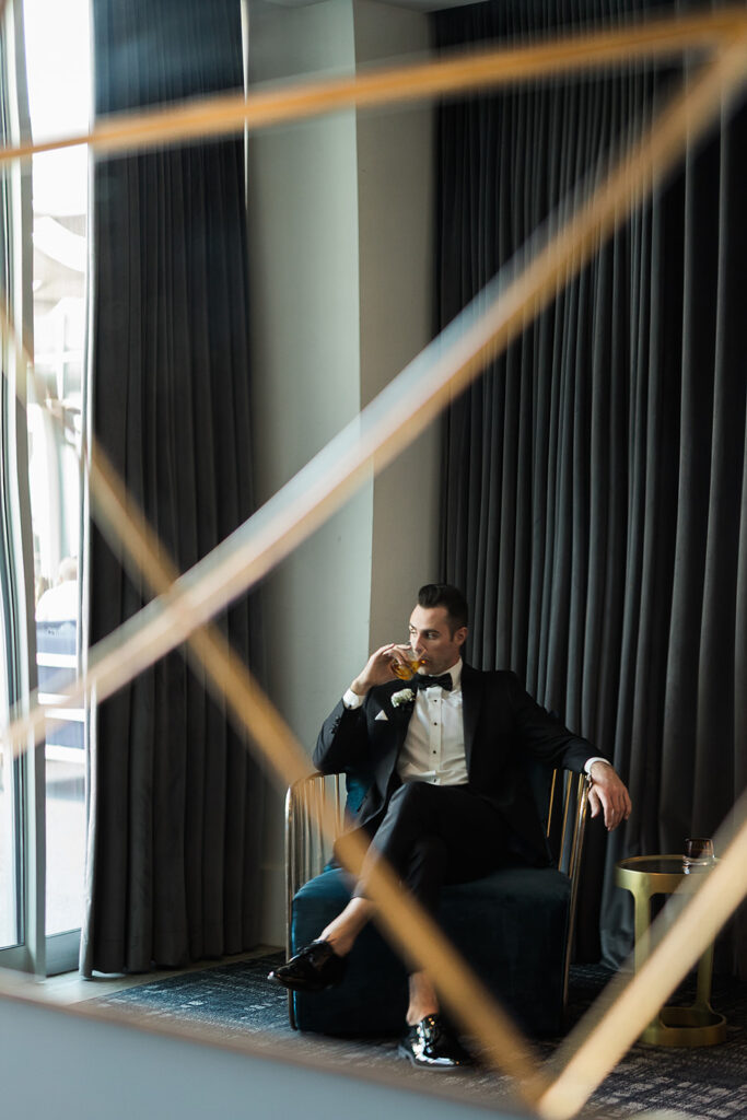 groom holding glass of whiskey in suit