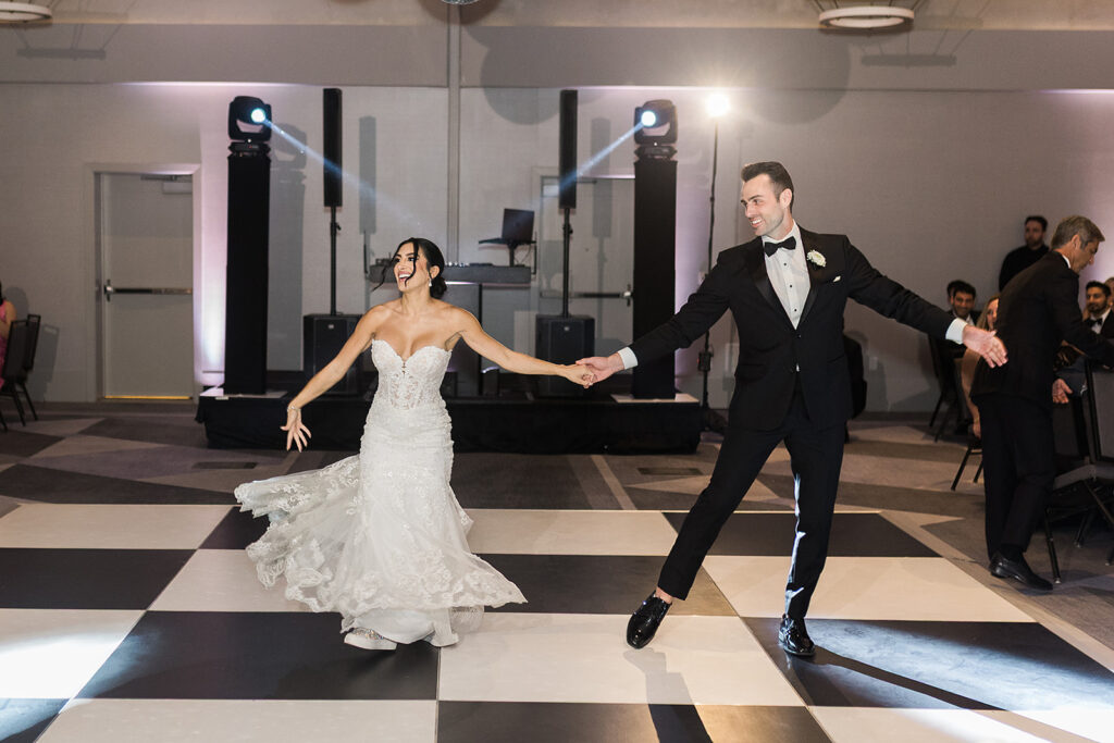 bride and groom twirl on dance floor during first dance