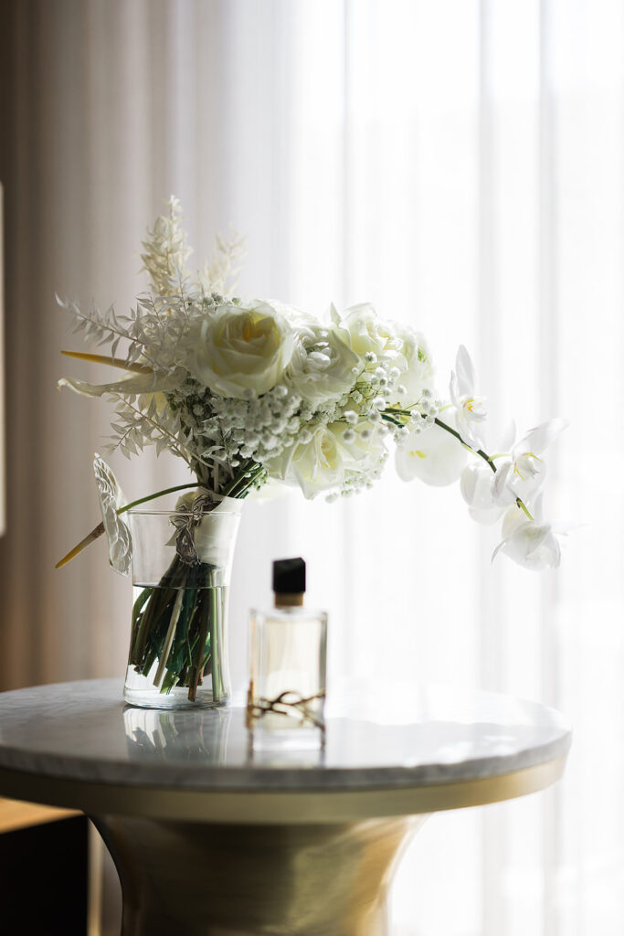 bridal boquet and perfume on table in hotel room