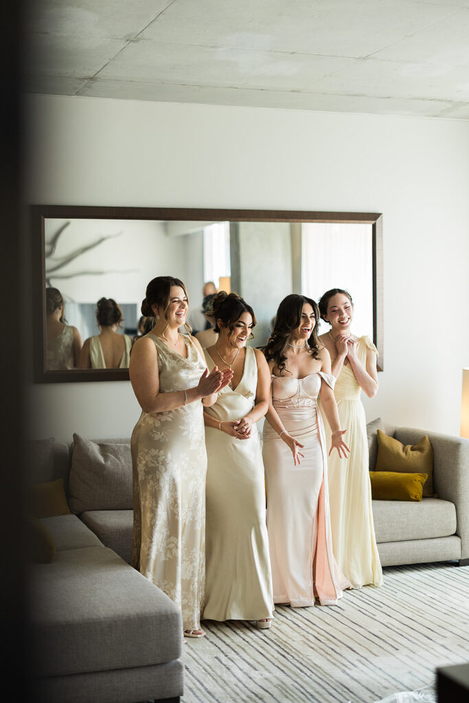 bridal party reacts in surprise to first look of bride in wedding gown