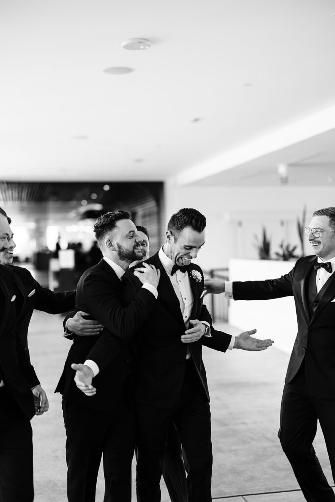 groomsmen laughing and touching groom's shoulder